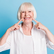 An older woman pointing to her new dental implants in Houston