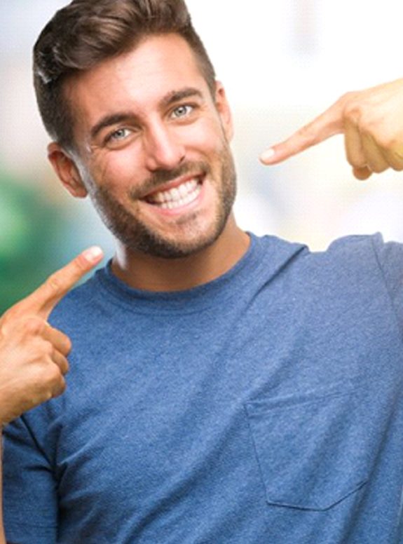 man pointing to his smile with dental crowns in Houston