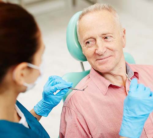 Older man smiling at emergency dentist in Houston during checkup