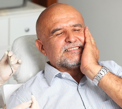 Man in need of tooth extraction holding cheek