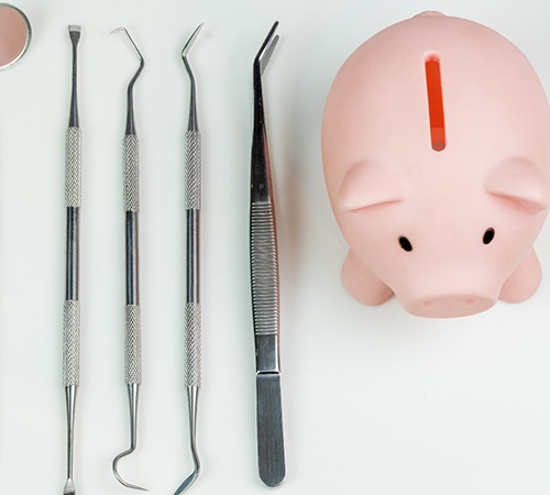 Piggy bank next to an array of dental tools